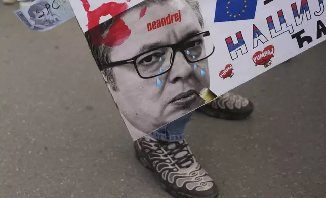 A woman holds a poster that shows Serbian President Aleksandar Vucic during a farewell ceremony for Serbia's protesting students embarking on 2,000-kilometer (1,200-mile) run to Brussels aimed to draw European Union attention to their months-long struggle against corruption and for the rule of law in Novi Sad, Serbia, Friday, April 25, 2025. (AP Photo/Darko Vojinovic)