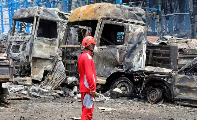 ADDING NAME OF PORT - In this photo provided by the Iranian Red Crescent Society on Sunday, April 27, 2025, a rescue worker stands in front of burnt vehicles after a massive explosion and fire rocked the Shahid Rajaei port near the southern port city of Bandar Abbas, Iran, on Saturday. (Iranian Red Crescent Society via AP)