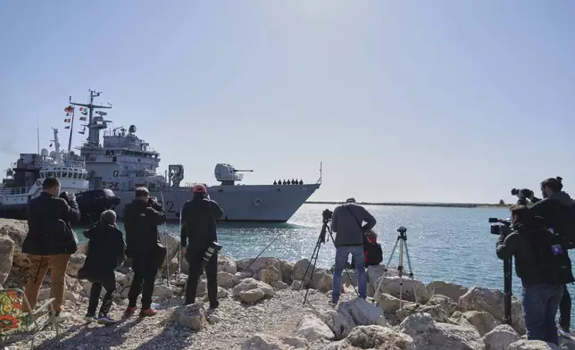 An Italian navy ship approaches the port next to videographers and photographers, as Italian authorities transfer 40 migrants with no permission to remain in the country to Italian-run migration detention centers in Albania, in Shengjin, northwestern Albania, Friday, April 11, 2025. (AP Photo/Vlasov Sulaj)
