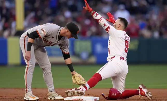 Los Angeles Angels' Zach Neto, right, gestures after hitting an RBI double as San Francisco Giants second baseman Tyler Fitzgerald puts a late tag on him during the XX inning of a baseball game Friday, April 18, 2025, in Anaheim, Calif. (AP Photo/Mark J. Terrill)