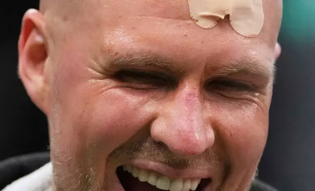 With his head bandaged after an injury, Boston Celtics center Kristaps Porzingis (8) laughs after defeating the Orlando Magic in game 2 of a first-round NBA playoff basketball series, Wednesday, April 23, 2025, in Boston. (AP Photo/Charles Krupa)
