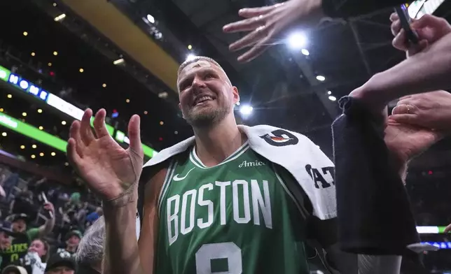 With his head bandaged after an injury, Boston Celtics center Kristaps Porzingis (8) is congratulated by fans after defeating the Orlando Magic in game 2 of a first-round NBA playoff basketball series, Wednesday, April 23, 2025, in Boston. (AP Photo/Charles Krupa)