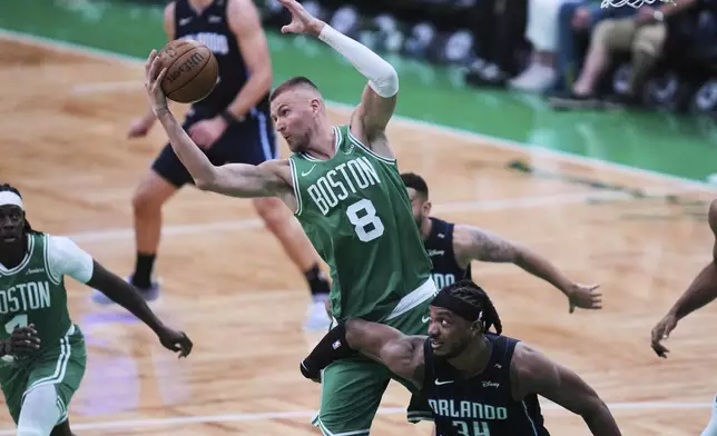 Boston Celtics center Kristaps Porzingis (8) grabs a rebound against Orlando Magic center Wendell Carter Jr. (34) during the second half in game 2 of a first-round NBA playoff basketball series, Wednesday, April 23, 2025, in Boston. (AP Photo/Charles Krupa)