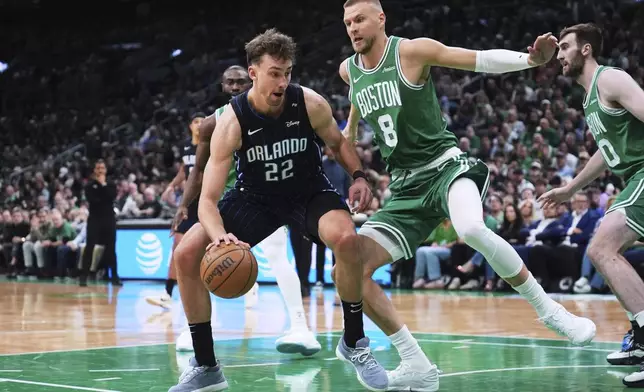 Orlando Magic forward Franz Wagner (22) drives to the basket against Boston Celtics center Kristaps Porzingis (8) during the first half in game 2 of a first-round NBA playoff basketball series, Wednesday, April 23, 2025, in Boston. (AP Photo/Charles Krupa)