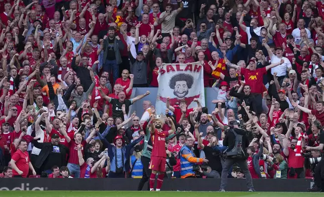 Liverpool's Mohamed Salah takes a selfie with a fans smartphone as he celebrates after scoring his side's fourth goal during the English Premier League soccer match between Liverpool and Tottenham Hotspur at Anfield in Liverpool, England, Sunday, April 27, 2025. (AP Photo/Jon Super)