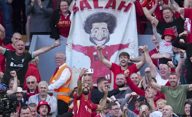 Liverpool's Mohamed Salah takes a selfie with a fans smartphone as he celebrates after scoring his side's fourth goal during the English Premier League soccer match between Liverpool and Tottenham Hotspur at Anfield in Liverpool, England, Sunday, April 27, 2025. (AP Photo/Jon Super)