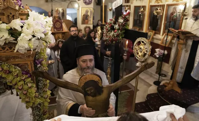 A Greek Orthodox priest holds a statue of Christ during a Good Friday reenactment of the Deposition of Jesus Christ at Agios Antonios church in the northern suburb of Chalandri during Holy Week in Athens, Greece, Friday, April 18, 2025. (AP Photo/Thanassis Stavrakis)