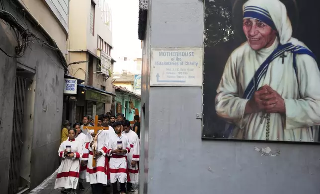 Altar boys and girls walk in a procession through an alley beside Saint Teresa's home, marking Good Friday, in Kolkata, India, Friday, April 18, 2025. (AP Photo/Bikas Das)