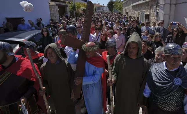 The deputy mayor of the Cypriot village of Kathikas Charalmbos Phylahtou, re-enacts the Procession to Calvary, or Christ carrying the cross to his crucifixion, through the village streets, flanked by villagers resembling Roman military and with the faithful following in procession in Kathikas village in Paphos district on holy Friday, April 18, 2025. (AP Photo/Petros Karadjias)