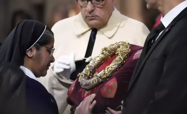 A nun touches the ancient relic that many Christians revere as Jesus Christ's "Crown of Thorns" during a ceremony to mark Good Friday at Notre Dame cathedral, Friday, April 18, 2025 in Paris. (AP Photo/Michel Euler)