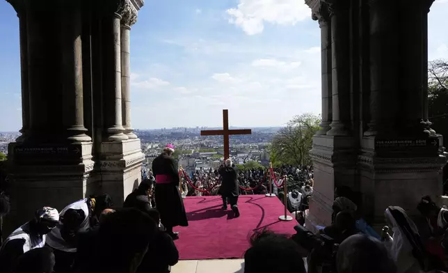 The cross is presented to the faithful during the Way of Cross ceremony to mark Good Friday, outside the Sacre Coeur basilica, Friday, April 18, 2025 in Paris. (AP Photo/Michel Euler)