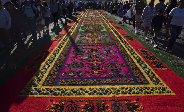 People walk past a sawdust carpet made as an offering from Catholics to Jesus Christ during a Holy Week procession in Antigua, Guatemala on Good Friday, April 18, 2025. (AP Photo/Moises Castillo)