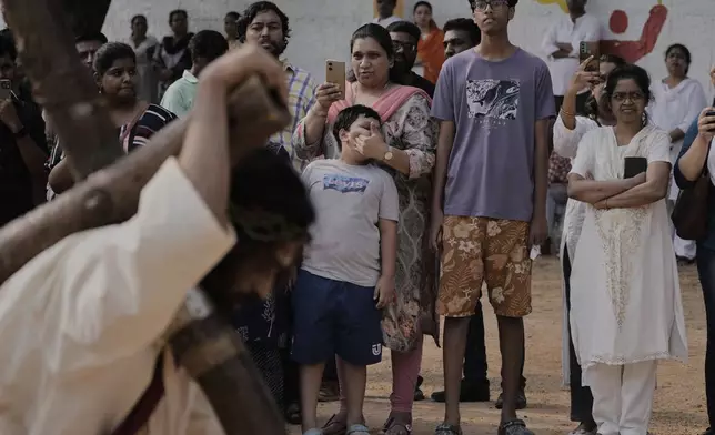 People watch as a man dressed as Jesus Christ reenacts the crucifixion of Jesus Christ to mark Good Friday in Hyderabad, India, Friday, April 18, 2025. (AP Photo/Mahesh Kumar A.)