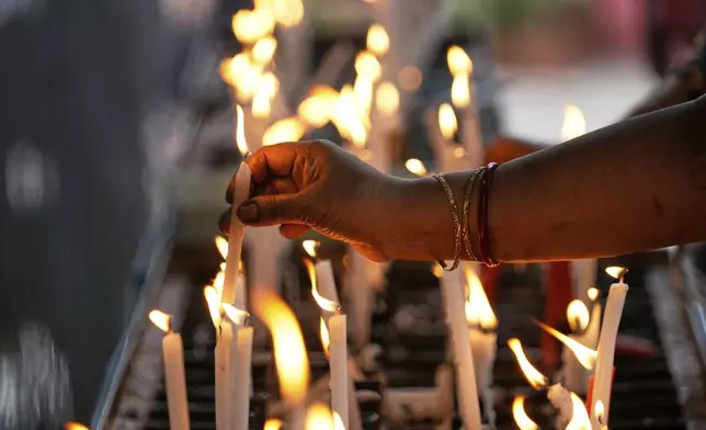 A Christian woman puts candle at the St. Teresa's Church marking Good Friday, in Kolkata, India, Friday, April 18, 2025. (AP Photo/Bikas Das)