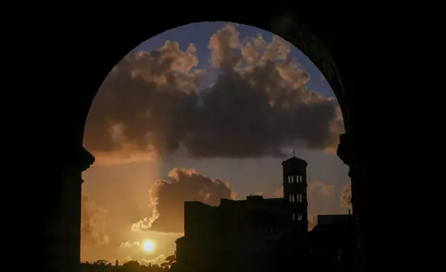 The sun sets over the Roman Forum before the start of the Via Crucis (Latin for 'way of the cross') procession marking the Catholic Good Friday, Friday, April 18, 2025. (AP Photo/Andrew Medichini)