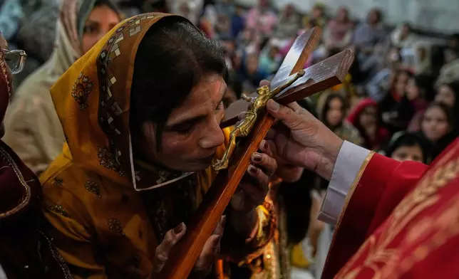 A Christian woman kisses the cross during a service at St. Anthony Church, marking Good Friday, in Lahore, Pakistan, Friday, April 18, 2025. (AP Photo/K.M. Chaudary)