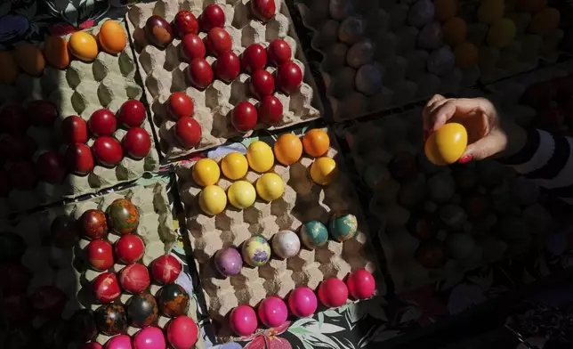 A buyer chooses hand decorated Easter eggs, on Orthodox Good Friday at a green market in Belgrade, Serbia, Friday, April 18, 2025. (AP Photo/Darko Vojinovic)