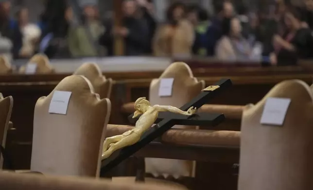 A crucifix rests on the chairs of St. Peter's Basilica at the Vatican during the preparations for the celebration of the passion of Christ, Friday, April 18, 2025. (AP Photo/Alessandra Tarantino)