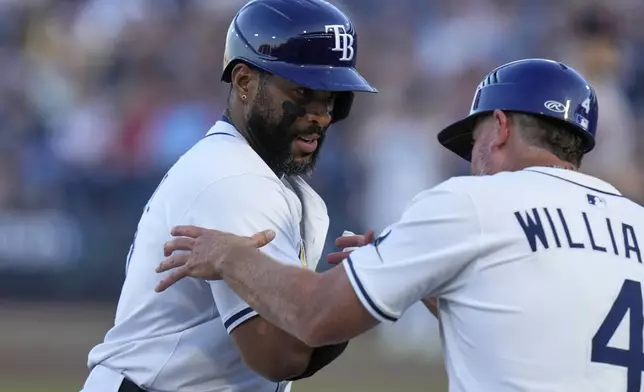 Tampa Bay Rays' Yandy Díaz, left, celebrates with third base coach Brady Williams after Diaz hit a solo home run off Boston Red Sox pitcher Tanner Houck during the first inning of a baseball game Monday, April 14, 2025, in Tampa, Fla. (AP Photo/Chris O'Meara)