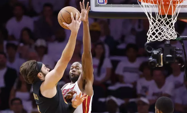 Cleveland Cavaliers guard Max Strus, left, shoots around Miami Heat forward Haywood Highsmith, second from left, during the first half in Game 4 of an NBA basketball first-round playoff series, Monday, April 28, 2025, in Miami. (AP Photo/Rhona Wise)