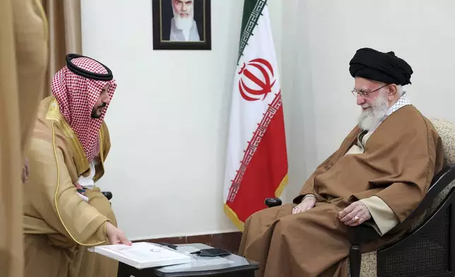 In this photo released by the official website of the office of the Iranian supreme leader, Saudi Arabia's Defense Minister Prince Khalid bin Salman, left, presents the message of the Saudi Arabia's king to the Supreme Leader Ayatollah Ali Khamenei during their meeting in Tehran, Iran, Thursday, April 17, 2025. (Office of the Iranian Supreme Leader via AP)
