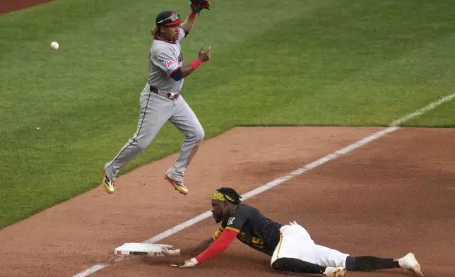 Pittsburgh Pirates' Oneil Cruz, right, slides safely into third as the ball gets past Cleveland Guardians third base José Ramírez during the sixth inning of a baseball game in Pittsburgh, Saturday, April 19, 2025. (AP Photo/Gene J. Puskar)