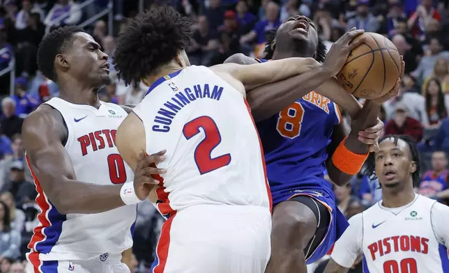 New York Knicks forward OG Anunoby (8) is fouled by Detroit Pistons guard Cade Cunningham (2) while going to the basket with Pistons' Jalen Duren (0) also defending during the first half of Game 4 of an NBA basketball first-round playoff series Sunday, April 27, 2025, in Detroit. (AP Photo/Duane Burleson)