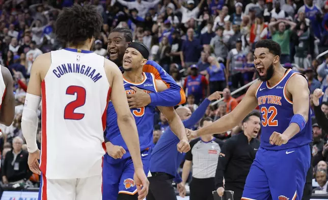 Detroit Pistons guard Cade Cunningham (2) walks across the court as New York Knicks center Ariel Hukporti, third from right, guard Josh Hart (3) and center Karl-Anthony Towns (32) celebrate after winning Game 4 of an NBA basketball first-round playoff series Sunday, April 27, 2025, in Detroit. (AP Photo/Duane Burleson)