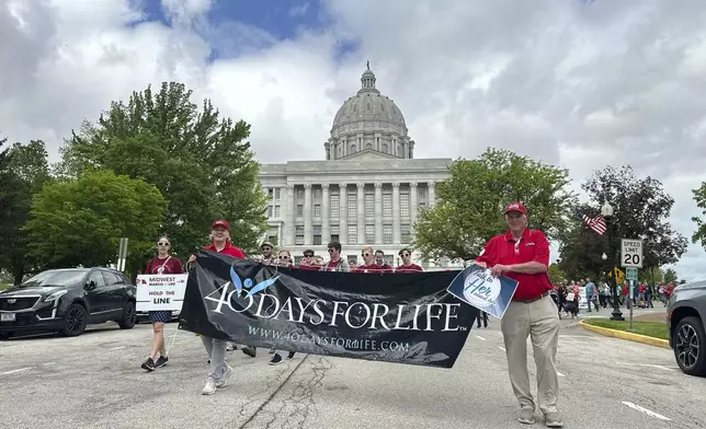 Participants in the Midwest March for Life walk through the streets of Jefferson City, Mo., with the state Capitol in the background on May 1, 2025. (AP Photo/David A. Lieb)