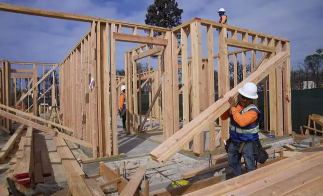 Workers rebuild a property destroyed by the Palisades Fire in the Pacific Palisades neighborhood of Los Angeles, Thursday, April 24, 2025. (AP Photo/Damian Dovarganes)
