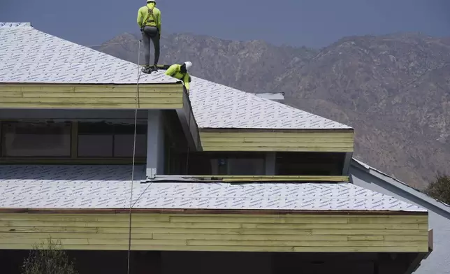 Construction workers install new roofing in Altadena, Calif., on Tuesday, April 22, 2025. (AP Photo/Damian Dovarganes)
