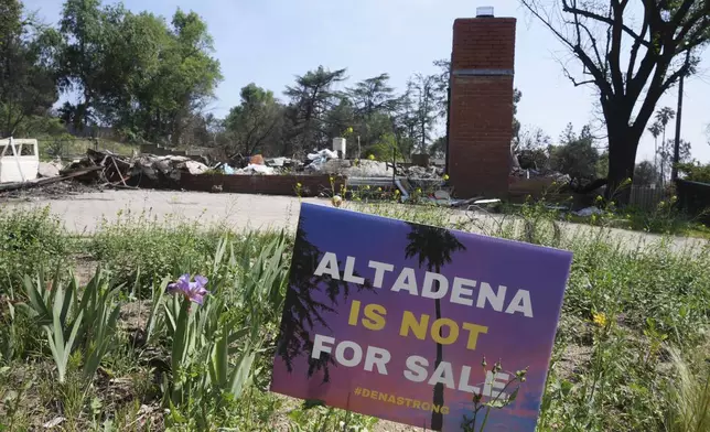 A sign reads "Altadena is not for sale" in front of a fire-damaged property in Altadena, Calif., Tuesday, April 22, 2025. (AP Photo/Damian Dovarganes)