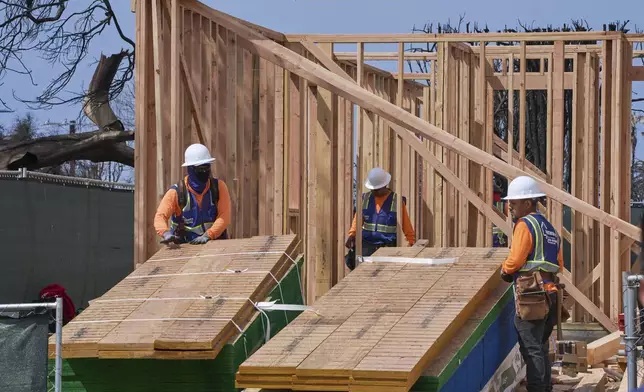 Workers rebuild a property destroyed by the Palisades Fire in the Pacific Palisades neighborhood of Los Angeles, Thursday, April 24, 2025. (AP Photo/Damian Dovarganes)