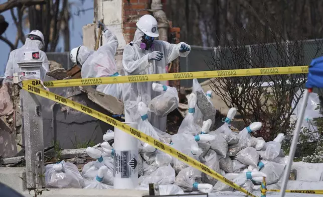 Cal/OSHA workers remove hazardous materials from a home destroyed by the Palisades Fire in the Pacific Palisades neighborhood of Los Angeles, Thursday, April 24, 2025. (AP Photo/Damian Dovarganes)