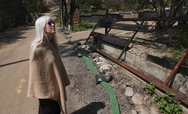 Kathryn Frazier looks at property, which was destroyed by the Eaton Fire in Altadena, Calif., on Tuesday, April 22, 2025. (AP Photo/Damian Dovarganes)