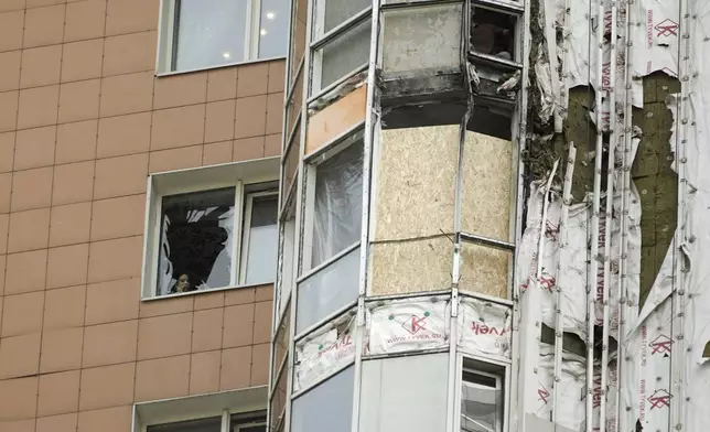 A woman speaks on the phone near a window of an apartment block of the Mirax Park residential complex damaged in a reported Ukrainian drone attack on Vernadsky Avenue in Moscow, Russia, Thursday, May 29, 2025. (AP Photo)