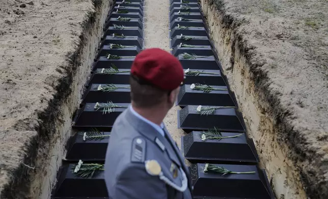 Small coffins with the remains of fallen German soldiers of WWII are placed in the mass grave during a funeral service at a memorial site for fallen soldiers in Halbe, Germany, Wednesday, April 30, 2025. (AP Photo/Ebrahim Noroozi)