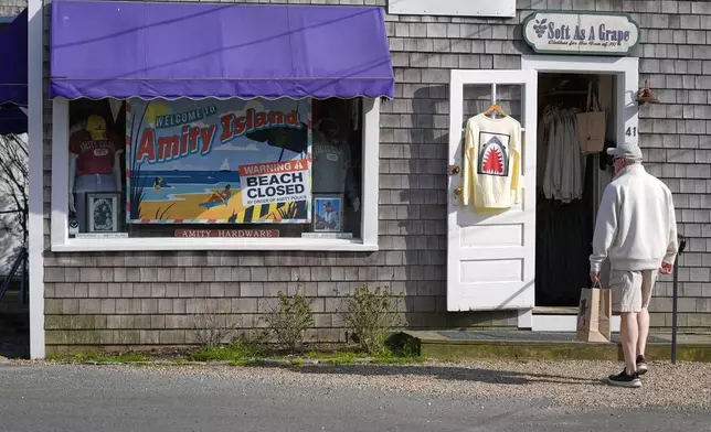 A visitor arrives at a shop selling Jaws-related souvenirs, Wednesday, May 14, 2025, in Edgartown, Mass. (AP Photo/Robert F. Bukaty)