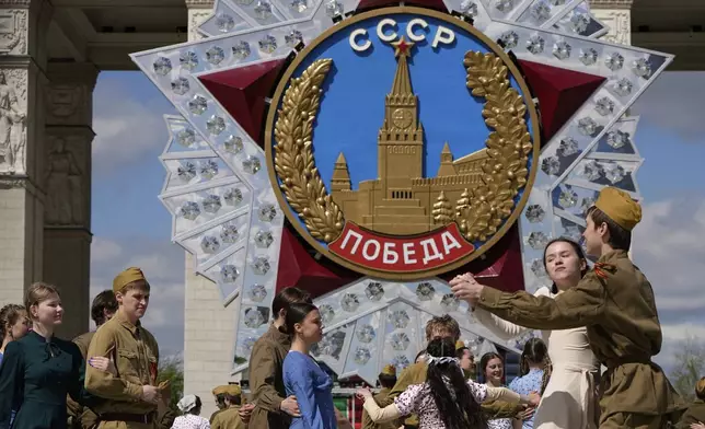 Moscow students dressed in the fashion of the middle of the last century and Soviet style uniform perform "Victory Waltz" as a part of Victory Day celebration in front of the a model of the main Soviet order, the Order of Victory at the historical gate of VDNKh, The Exhibition of Achievements of National Economy in Moscow, Russia, Tuesday, May 6, 2025. (AP Photo/Alexander Zemlianichenko)
