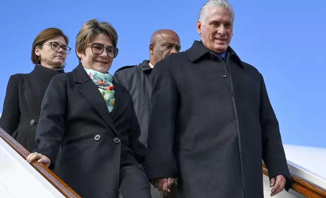 Cuba's President Miguel Diaz-Canel, right, and his wife Lis Cuesta Peraza, left, leave a plane upon arrival at the Vnukovo airport ahead of celebrations of the 80th anniversary of the Soviet Union's victory over Nazi Germany during the World War II, in Moscow, Russia, Tuesday, May 6, 2025. (Kirill Zykov/Photo host agency RIA Novosti via AP)
