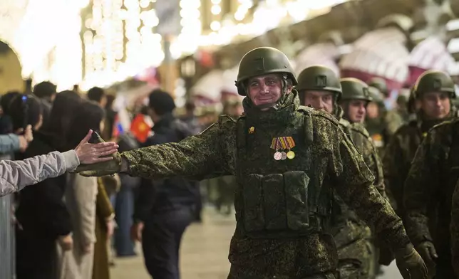A decorated Russian soldier, a participant in the military operation in Ukraine, is greeted by a woman as soldiers march past the GUM department store toward Red Square to attend a rehearsal for the Victory Day military parade in Moscow, Russia, on Saturday, May 3, 2025. (AP Photo/Alexander Zemlianichenko)