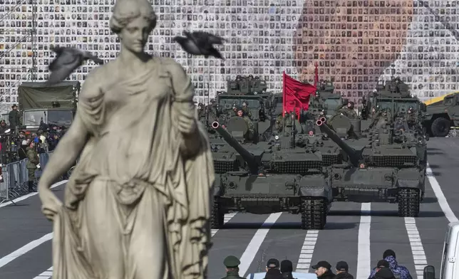 Russian tanks roll during a rehearsal for the Victory Day military parade at the Dvortsovaya (Palace) Square in St. Petersburg, Russia, Saturday, May 3, 2025, with a huge banner with portraits of participants of World War II in the background. (AP Photo/Dmitri Lovetsky)