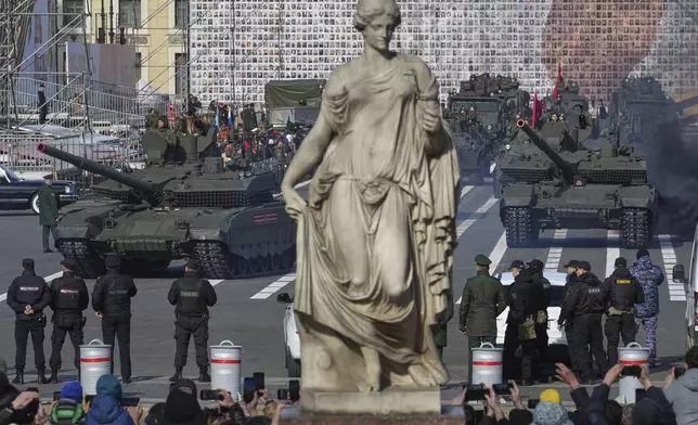 Russian tanks roll during a rehearsal for the Victory Day military parade at the Dvortsovaya (Palace) Square in St. Petersburg, Russia, Saturday, May 3, 2025, with a huge banner with portraits of participants of World War II in the background. (AP Photo/Dmitri Lovetsky)