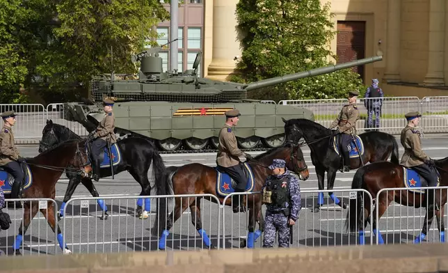 Riders pass by Russian armored vehicle ahead of a dress rehearsal for the Victory Day military parade in Moscow, Russia, on Wednesday, May 7, 2025. (AP Photo/Alexander Zemlianichenko)