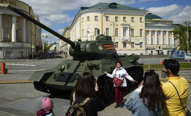 A woman poses for a photo next to a Soviet T-24 battle tank displayed at Manezhnaya square ahead of celebrations of the 80th anniversary of the Soviet Union's victory over Nazi Germany during the World War II, in Moscow, Russia, Tuesday, May 6, 2025. (AP Photo/Pavel Bednyakov)