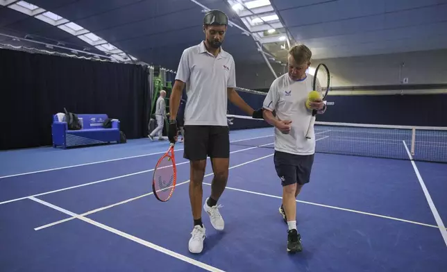 Blind tennis champion Naqi Rizvi and tennis coach Lee Neale walk on court during a visually impaired tennis training session in London, Tuesday, May 20, 2025. (AP Photo/Kin Cheung)