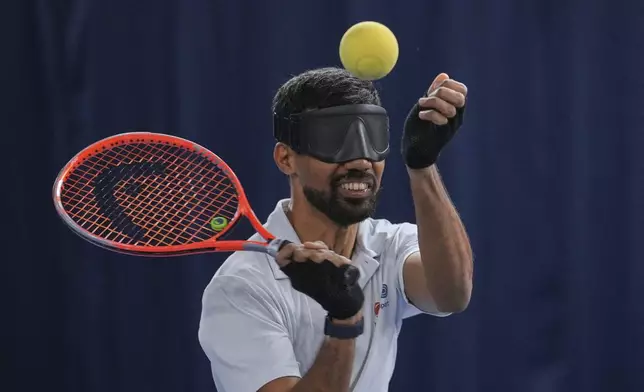 Blind tennis champion Naqi Rizvi serves the ball during a visually impaired tennis training session in London, Tuesday, May 20, 2025. (AP Photo/Kin Cheung)