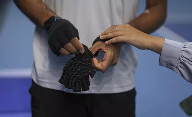 Blind tennis champion Naqi Rizvi is assisted by his wife Zara as he prepares for a visually impaired tennis training session in London, Tuesday, May 20, 2025. (AP Photo/Kin Cheung)