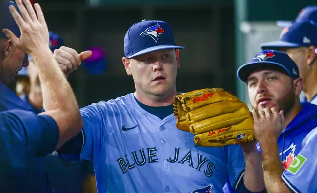 Toronto Blue Jays' starting pitcher Paxton Schultz is greeted by teammates in the dugout after being taken out of the game during the third inning of a baseball game against the Texas Rangers, Wednesday, May 28, 2025, in Arlington, Texas. (AP Photo/Ronaldo Bolaños)