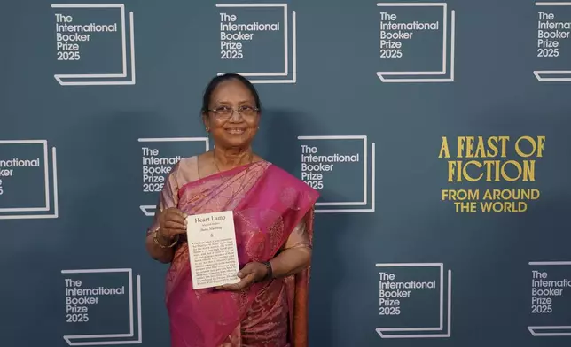 Banu Mushtaq, author of 'Heart Lamp' holds her book as she poses for photographers upon arrival for the International Booker Prize, in London, Tuesday, May 20, 2025.(AP Photo/Alberto Pezzali)